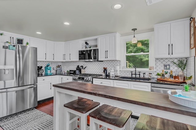 kitchen with a kitchen breakfast bar, butcher block counters, sink, and appliances with stainless steel finishes