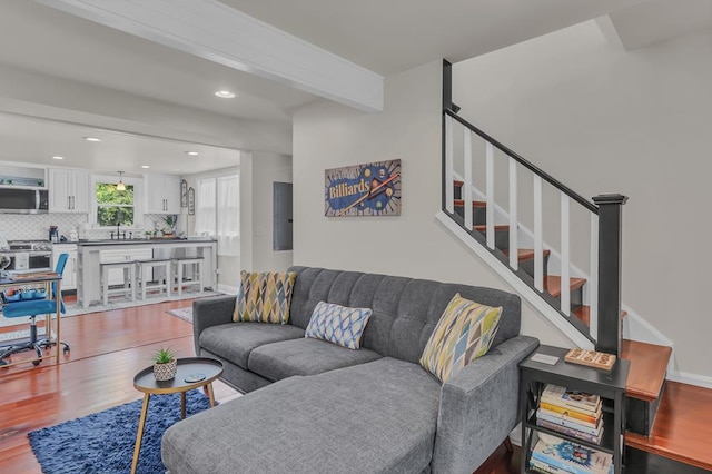 living room featuring beamed ceiling, hardwood / wood-style floors, and sink