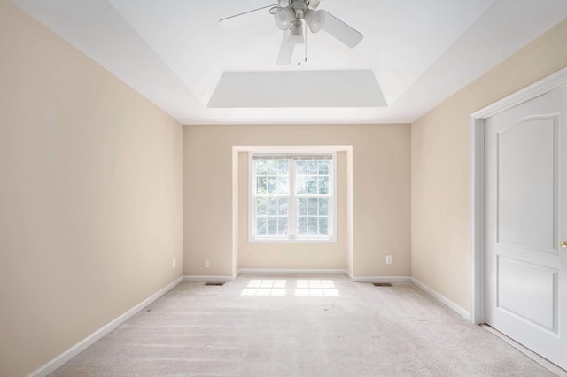 carpeted spare room with a tray ceiling and ceiling fan