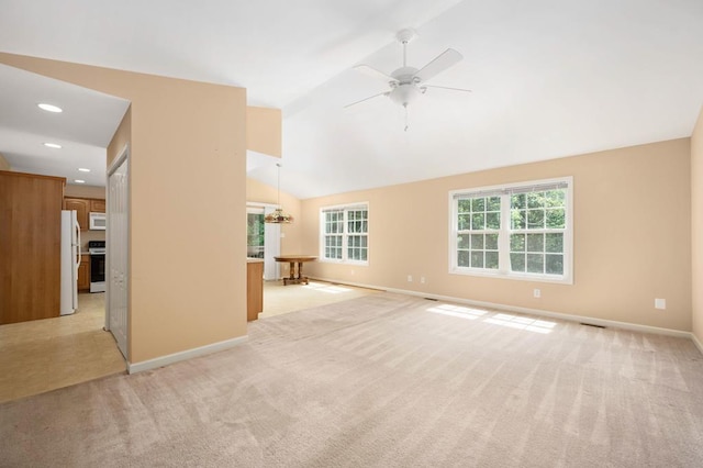 unfurnished living room with ceiling fan with notable chandelier, light colored carpet, and lofted ceiling