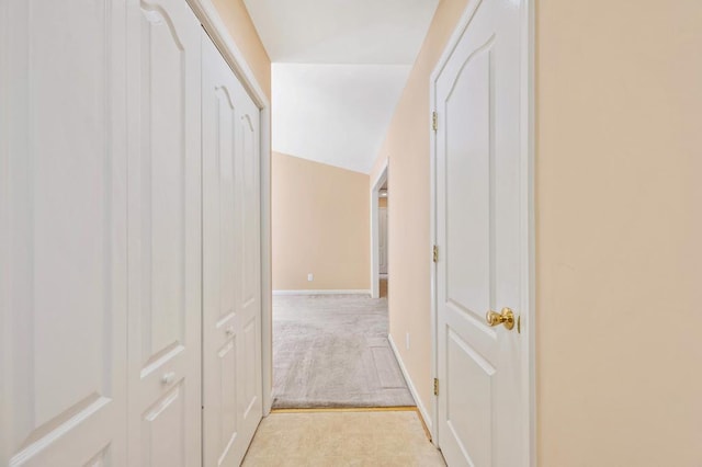 corridor featuring light colored carpet and lofted ceiling