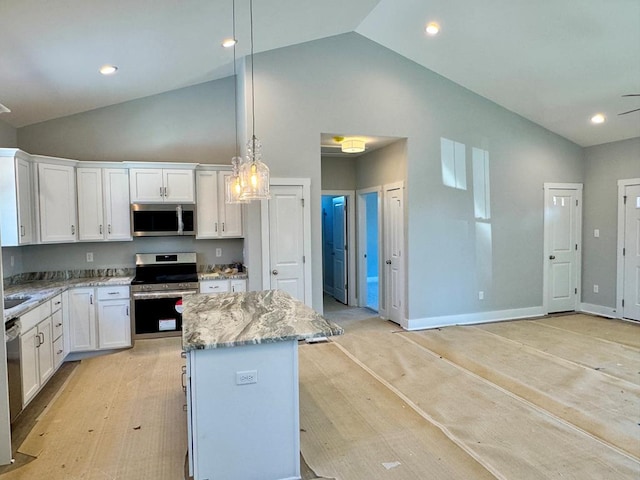 kitchen with appliances with stainless steel finishes, a kitchen island, decorative light fixtures, white cabinetry, and light stone counters