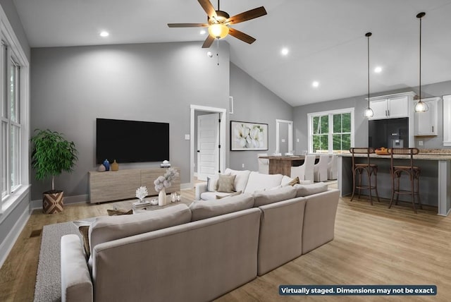 living room with ceiling fan, light wood-type flooring, and high vaulted ceiling