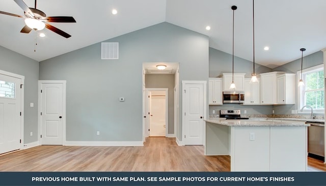 kitchen with light stone counters, white cabinetry, a center island, and stainless steel appliances