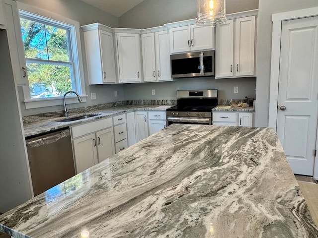 kitchen with light stone countertops, stainless steel appliances, white cabinets, and sink