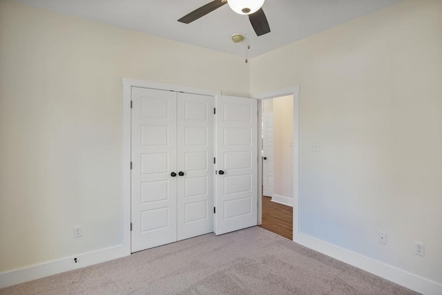 unfurnished bedroom with ceiling fan, a closet, and light carpet