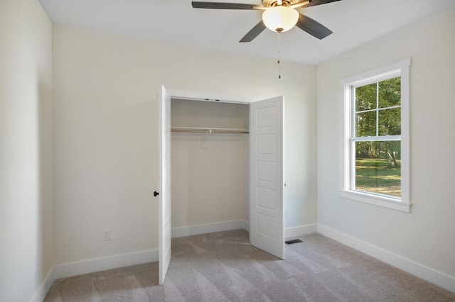 unfurnished bedroom with multiple windows, ceiling fan, a closet, and light colored carpet