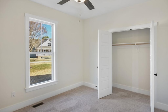 unfurnished bedroom featuring light carpet, multiple windows, a closet, and ceiling fan