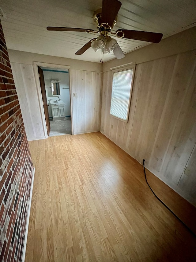 empty room featuring light hardwood / wood-style flooring, ceiling fan, and wood walls