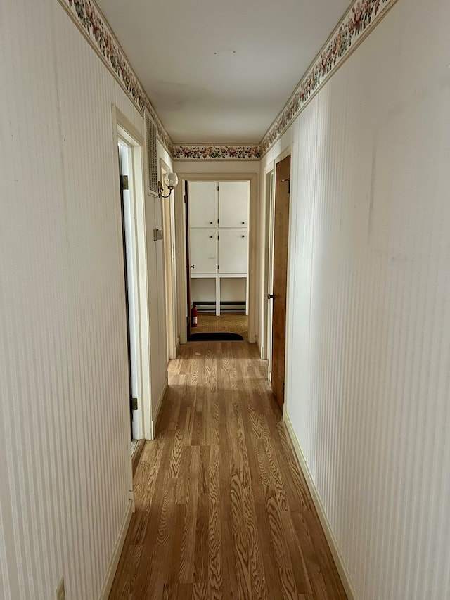 corridor featuring hardwood / wood-style floors and baseboard heating