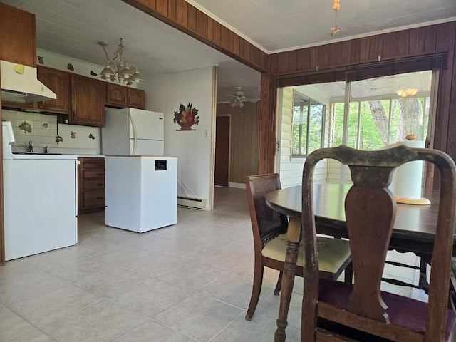 309 Riverview Dr, Heathsville, VA 22473 - dining area featuring wood walls, a baseboard heating unit, an inviting chandelier, crown molding, and light tile patterned floors