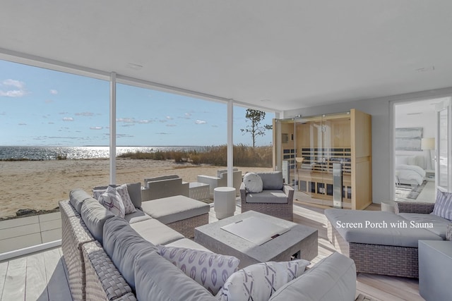 living room with a beach view, a water view, expansive windows, and hardwood / wood-style flooring