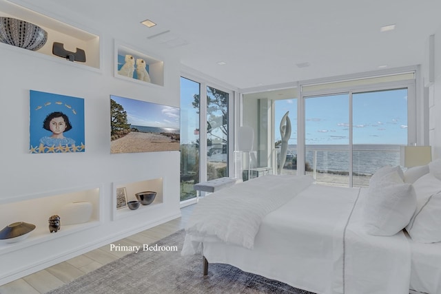 bedroom featuring hardwood / wood-style floors, floor to ceiling windows, a water view, and access to outside