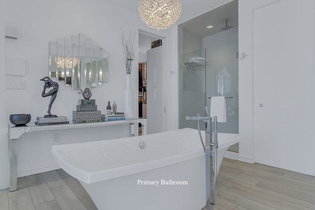 bathroom with a tub, wood-type flooring, and an inviting chandelier