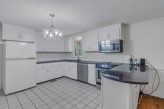 kitchen with kitchen peninsula, a textured ceiling, stainless steel appliances, sink, and white cabinetry