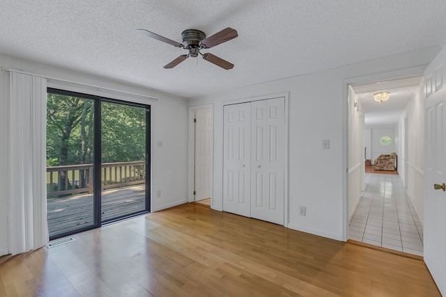 unfurnished bedroom featuring access to outside, ceiling fan, a closet, and a textured ceiling