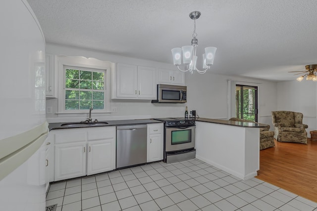 kitchen featuring white cabinetry, kitchen peninsula, decorative light fixtures, light tile patterned floors, and appliances with stainless steel finishes