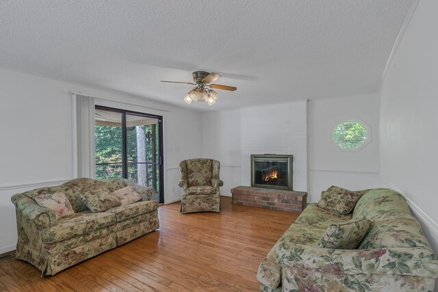 living room with a textured ceiling, light wood-type flooring, and ceiling fan