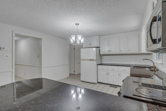 kitchen with white cabinets, white refrigerator, light tile patterned floors, and range