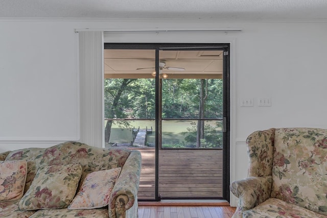 living room featuring ceiling fan, light hardwood / wood-style flooring, and a textured ceiling