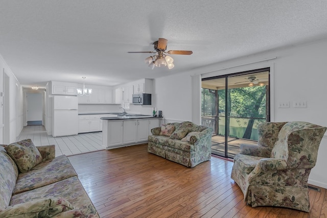 living room featuring a chandelier, a textured ceiling, light hardwood / wood-style flooring, and sink