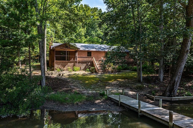 rear view of house with a deck with water view and a sunroom