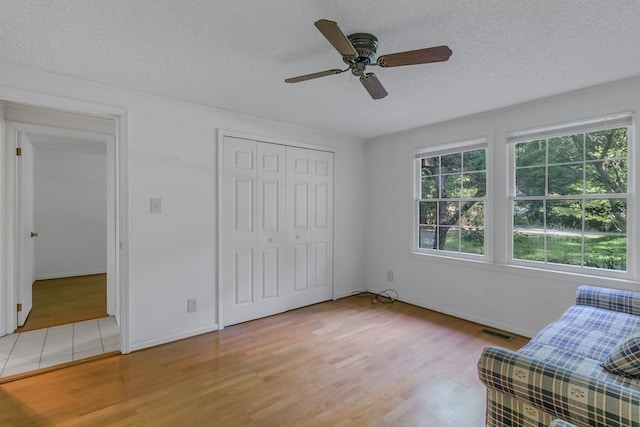 unfurnished room with a textured ceiling, light hardwood / wood-style floors, and ceiling fan