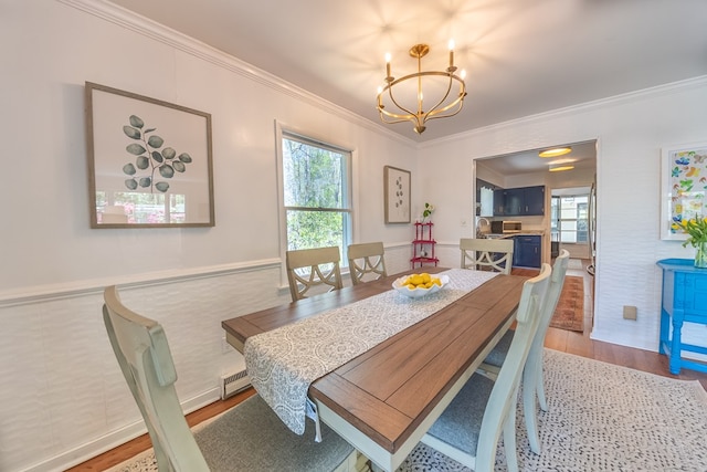 dining area with sink, crown molding, a chandelier, and light wood-type flooring