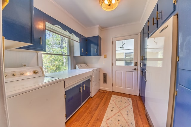 washroom with washing machine and dryer, crown molding, cabinets, and wood-type flooring