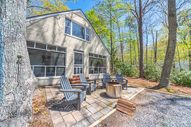 view of patio with an outdoor fire pit and a sunroom