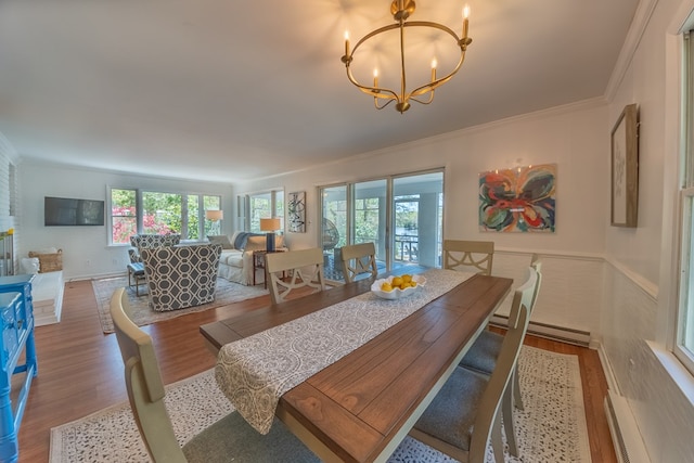 dining area featuring crown molding, a baseboard radiator, a healthy amount of sunlight, and a notable chandelier