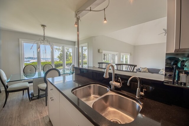 1032 Fishing Bay Rd, Deltaville, VA 23043 - kitchen with light wood-style flooring, white cabinets, hanging light fixtures, vaulted ceiling, and dark stone countertops