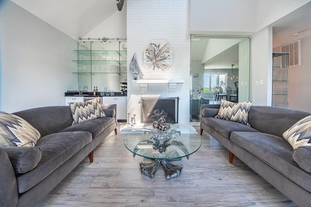 1032 Fishing Bay Rd, Deltaville, VA 23043 - living room featuring wood finished floors, a brick fireplace, and high vaulted ceiling