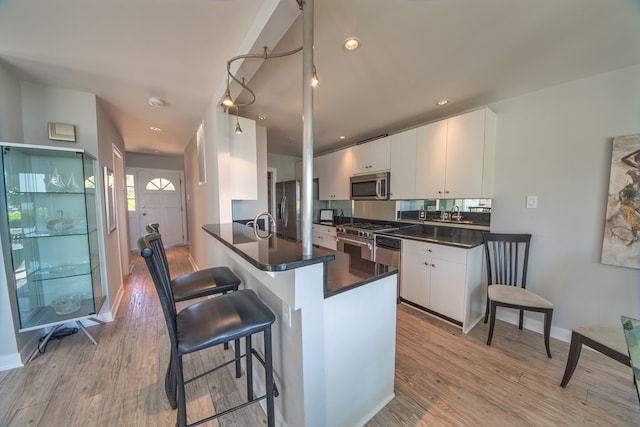 1032 Fishing Bay Rd, Deltaville, VA 23043 - kitchen with appliances with stainless steel finishes, dark countertops, light wood-type flooring, white cabinets, and recessed lighting