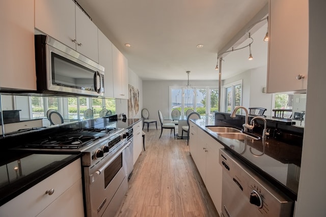 1032 Fishing Bay Rd, Deltaville, VA 23043 - kitchen with appliances with stainless steel finishes, light wood-style floors, white cabinets, decorative light fixtures, and a chandelier