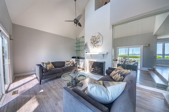 1032 Fishing Bay Rd, Deltaville, VA 23043 - living room with high vaulted ceiling, ceiling fan, a fireplace, and wood finished floors