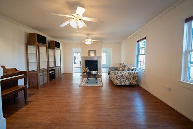 living room featuring baseboards, a fireplace, wood finished floors, and crown molding