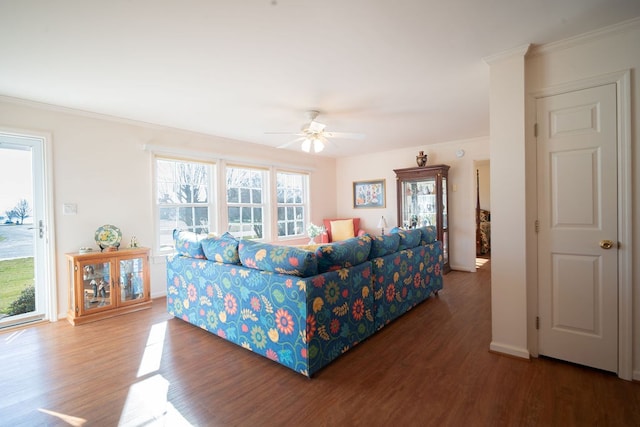 living area with crown molding, wood finished floors, baseboards, and ceiling fan