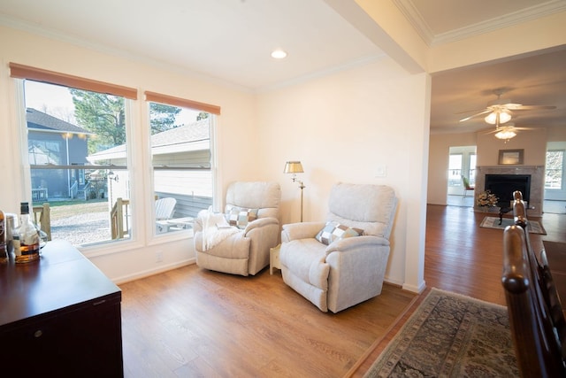 living room with a fireplace, baseboards, light wood-style floors, and ornamental molding