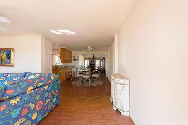 living area featuring ornamental molding, baseboards, and wood finished floors