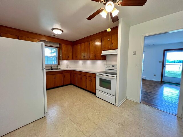 2048 Lake Rd, Lottsburg, VA 22511 - kitchen with white appliances, under cabinet range hood, brown cabinetry, a sink, and light countertops