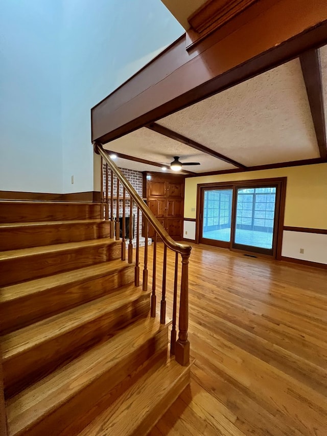 stairs featuring ceiling fan, hardwood / wood-style flooring, and a textured ceiling