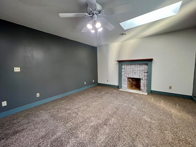 unfurnished living room featuring ceiling fan, a fireplace, a skylight, and carpet floors