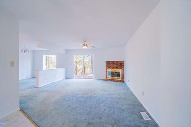 unfurnished living room featuring ceiling fan with notable chandelier, light colored carpet, and a fireplace