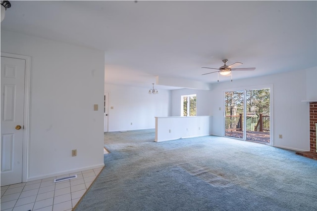 unfurnished living room with a fireplace, light colored carpet, and ceiling fan with notable chandelier