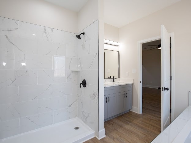 bathroom featuring hardwood / wood-style flooring, vanity, and a tile shower