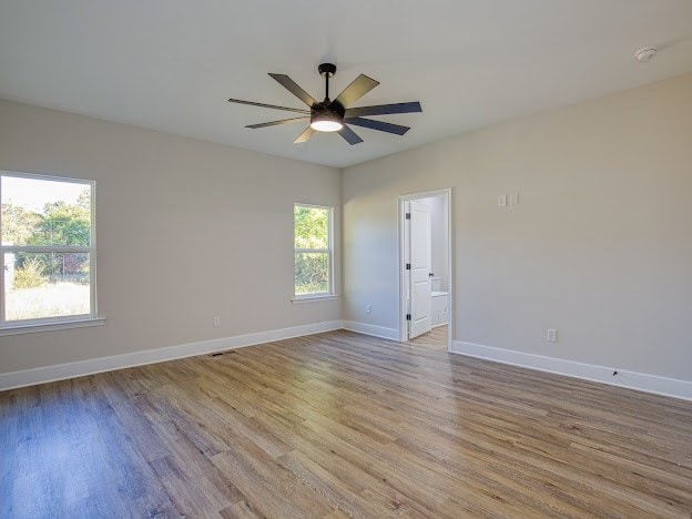 empty room with ceiling fan and light hardwood / wood-style flooring