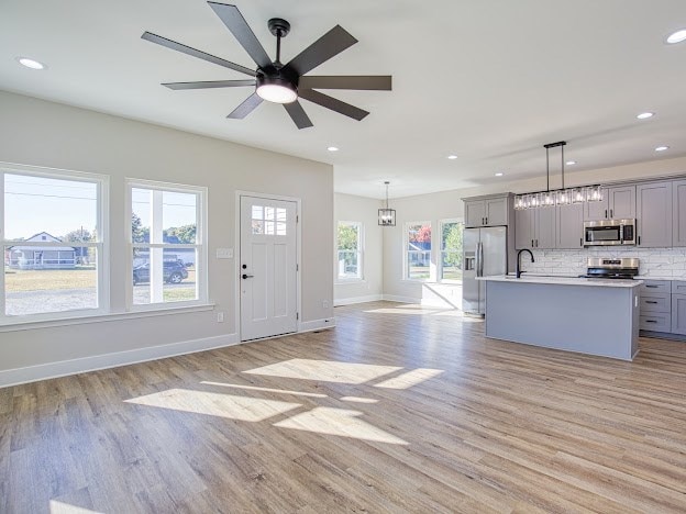 interior space featuring light hardwood / wood-style flooring, ceiling fan with notable chandelier, and sink