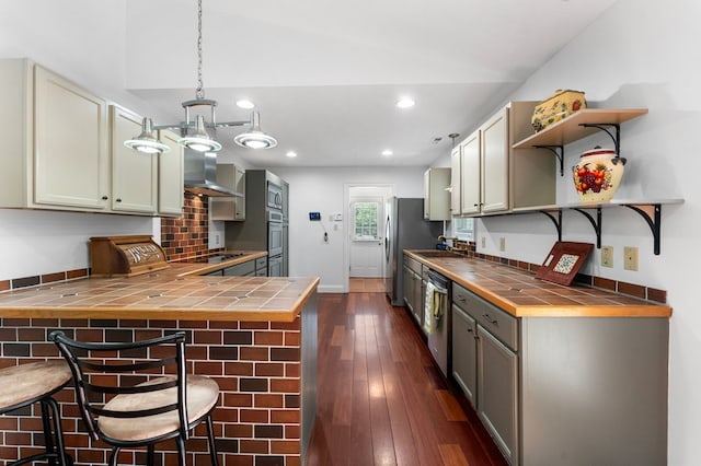 326 Chase St, Kilmarnock, VA 22482 - kitchen featuring tile countertops, stainless steel appliances, open shelves, wall chimney range hood, and recessed lighting