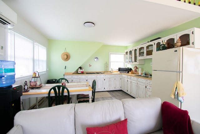 1150 Brammer Dr, Heathsville, VA 22473 - kitchen with stainless steel microwave, freestanding refrigerator, a wall mounted AC, stovetop, and glass insert cabinets